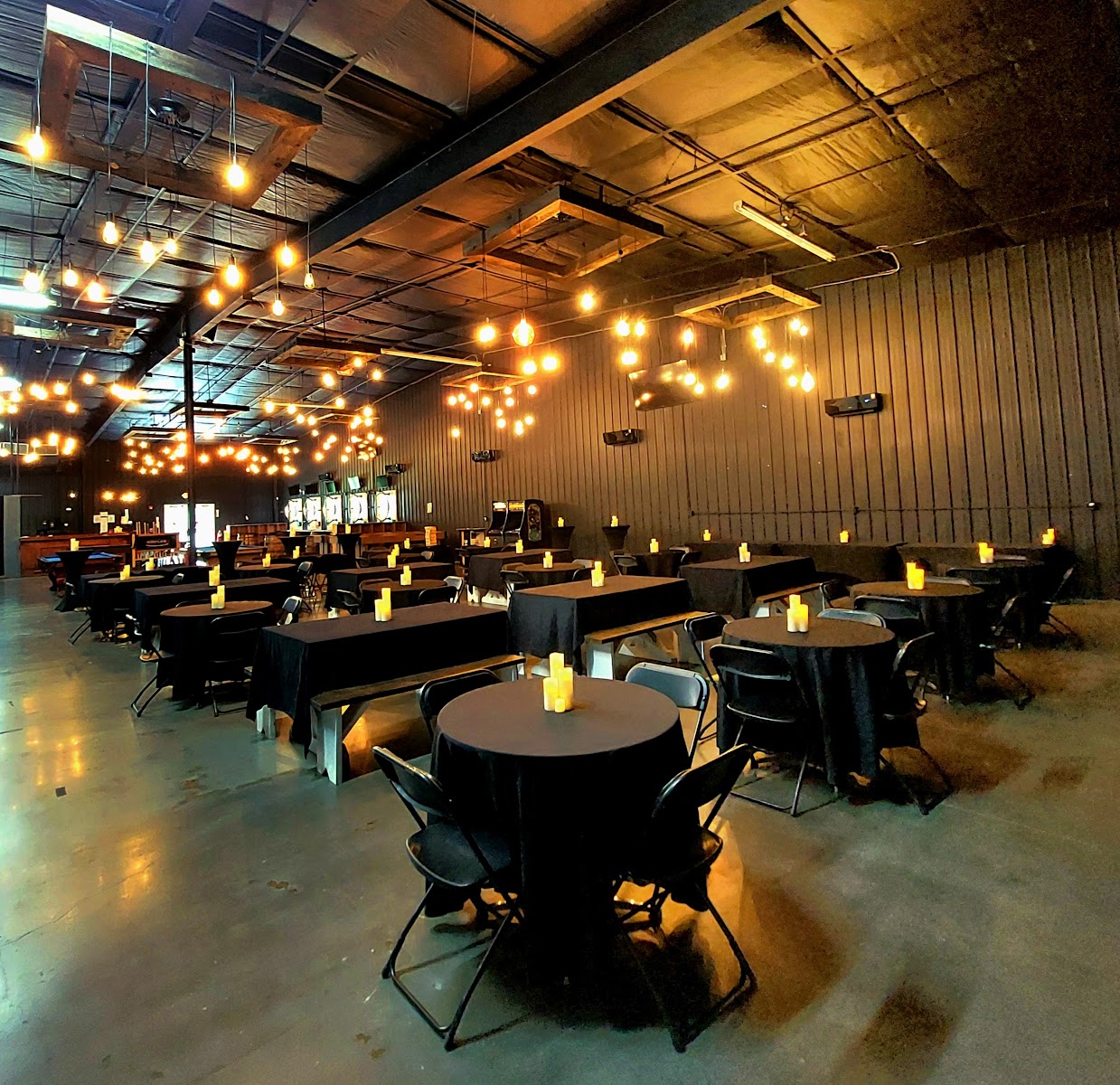 Wide prepared event-room layout beneath warm string lighting